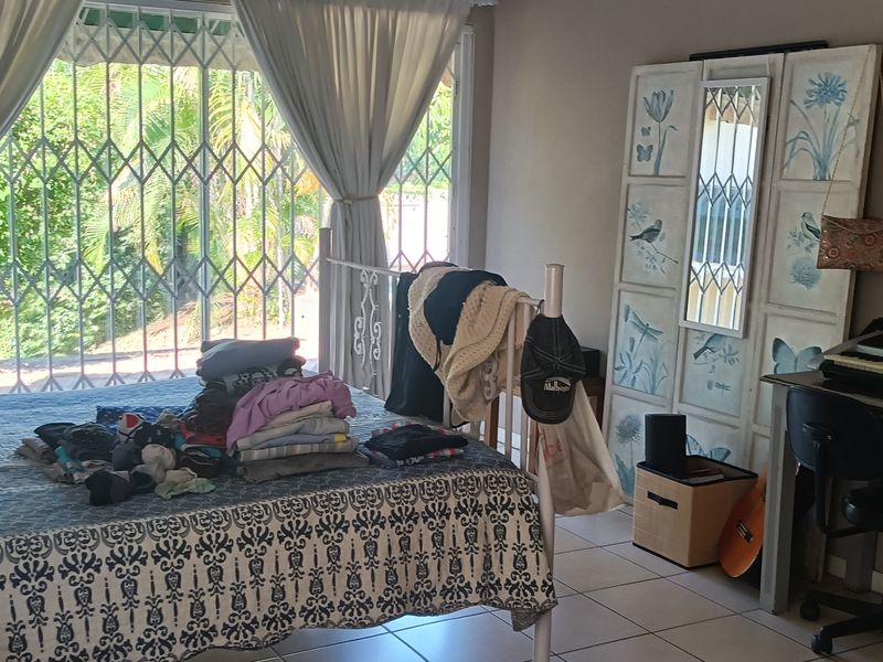 A bedroom featuring tiled flooring and a large sliding door with an integrated security gate, providing access to the exterior.