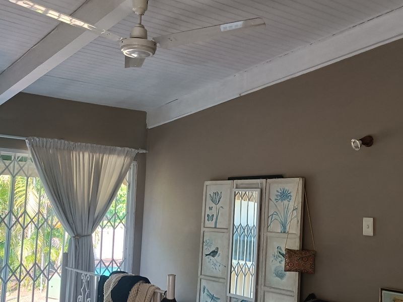 A bedroom featuring a timber panelled ceiling with a ceiling fan and a sliding door with security gate access to the exterior.