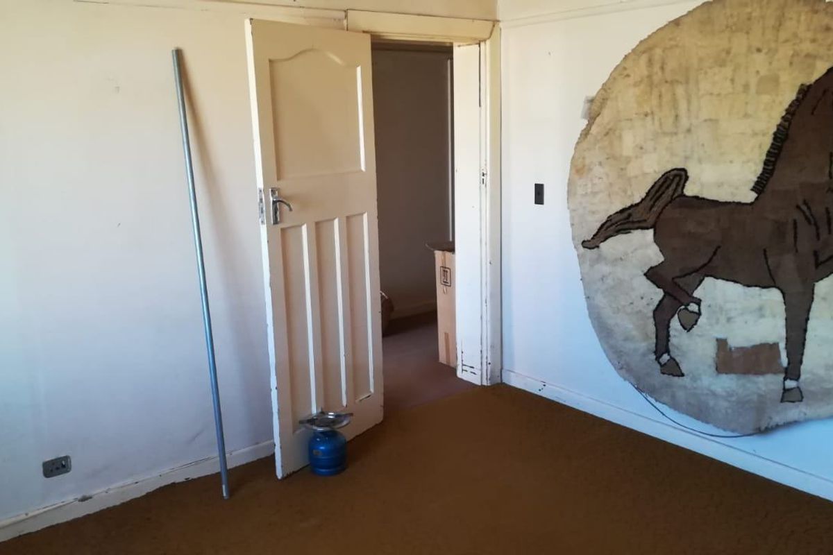 A vacant bedroom featuring carpet flooring and a traditional timber door, requiring cosmetic updates to improve its overall appeal.