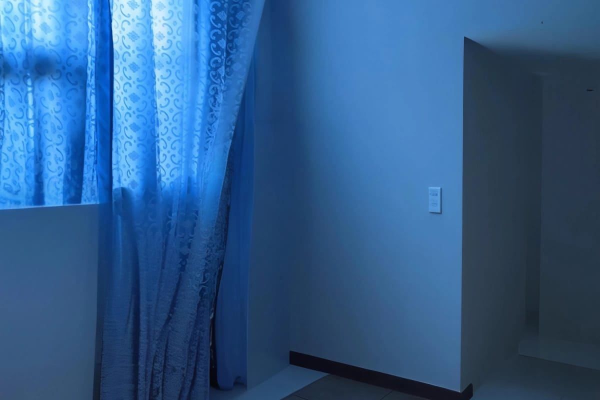 An empty bedroom featuring tiled flooring and a neutral wall finish, offering a blank canvas for interior design.