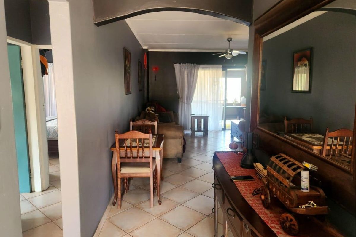 A living area featuring tiled flooring, a ceiling fan, and a sliding glass door leading to an outdoor space, connected by an interior archway.