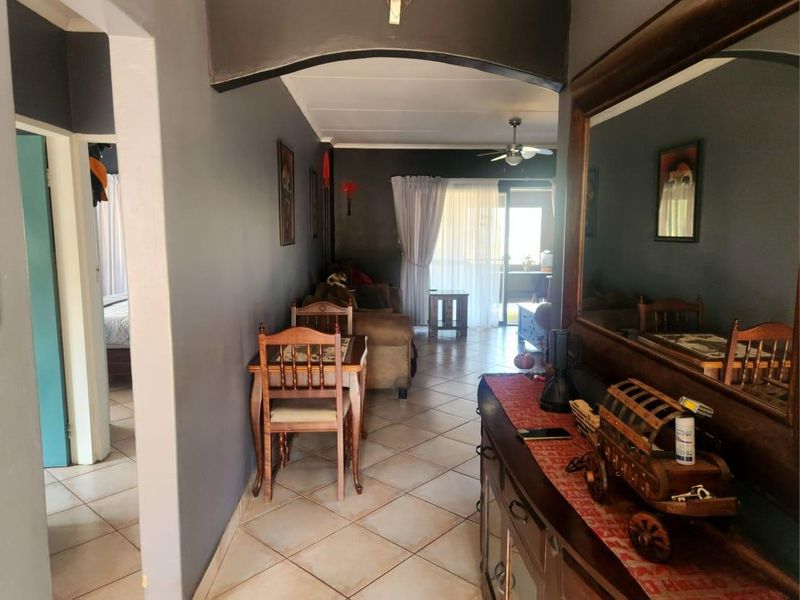 A living area featuring tiled flooring, a ceiling fan, and a sliding glass door leading to an outdoor space, connected by an interior archway.