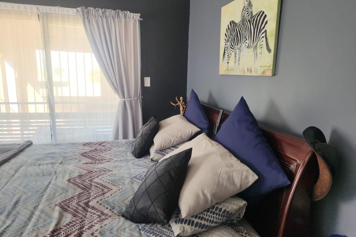 A bedroom featuring dark grey accent walls and a sliding glass door with an integrated security gate.