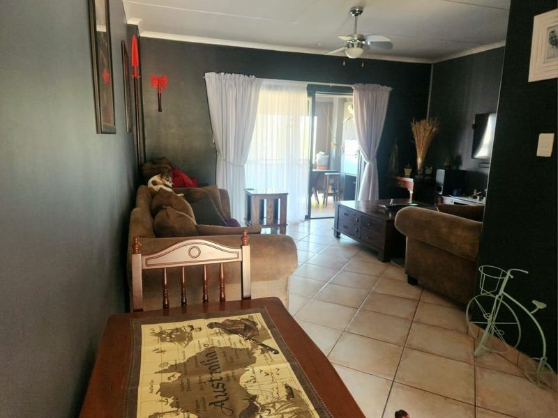 A living room featuring dark painted walls, tiled flooring, and a ceiling fan, with direct access to an outdoor patio area through sliding glass doors.