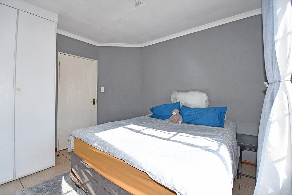 A bedroom featuring tiled flooring, a built-in wardrobe, and neutral grey wall finishes.