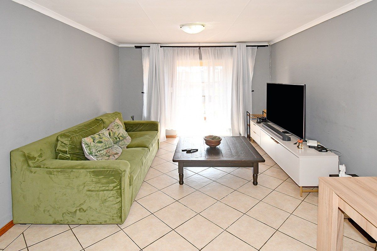 A functional living room featuring neutral tiled flooring and a sliding glass door providing natural light and access to the exterior.