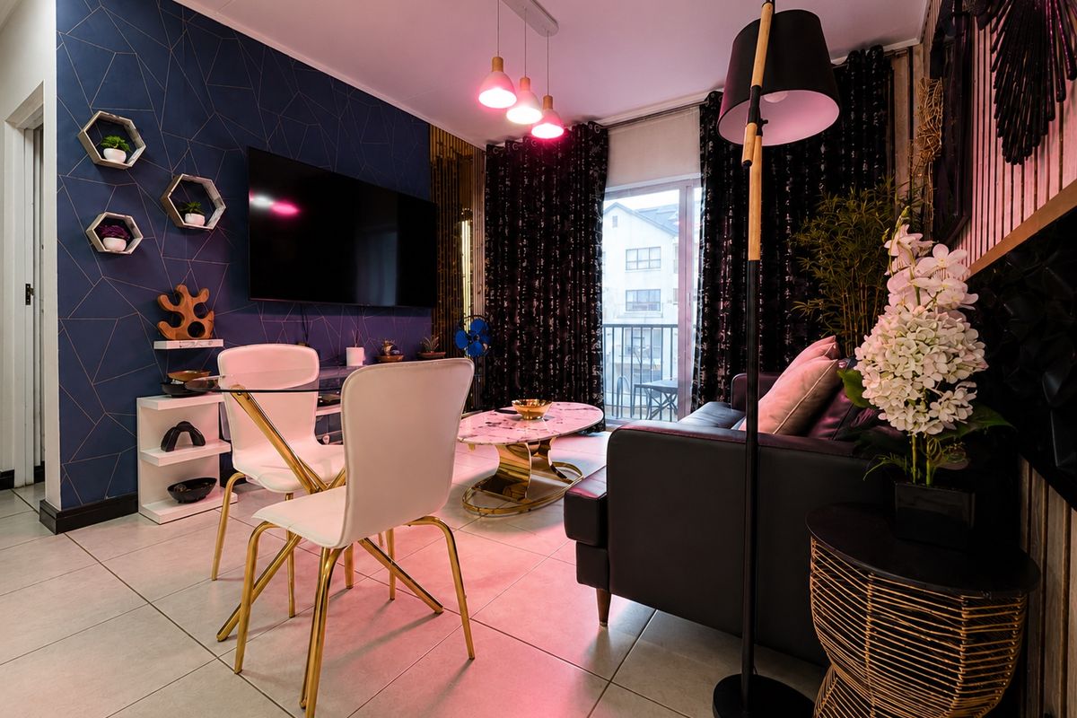 A modern living room featuring tiled flooring, decorative accent wall, and a sliding glass door providing access to a balcony.