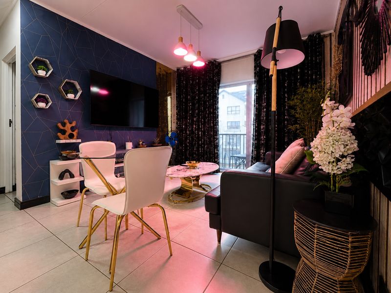 A modern living room featuring tiled flooring, decorative accent wall, and a sliding glass door providing access to a balcony.