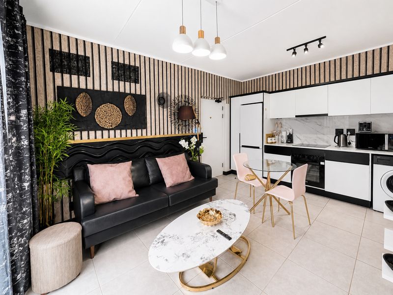 Modern open-plan living area featuring a contemporary kitchen with built-in appliances, sleek cabinetry, and stylish decorative wall paneling.
