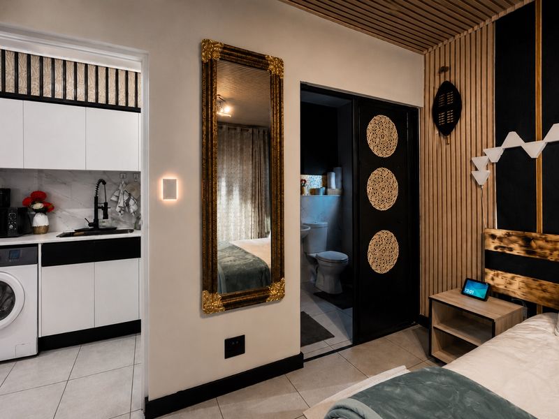 Modern open-plan apartment interior featuring slatted timber wall accents, a sleek kitchen with marble-look backsplash, and a private bathroom with sliding door access.