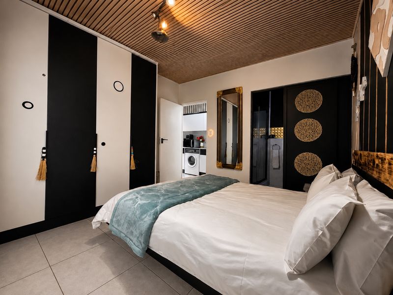 Modern bedroom featuring a unique slatted timber ceiling, large built-in wardrobes with a monochrome design, and direct access to an en-suite bathroom.