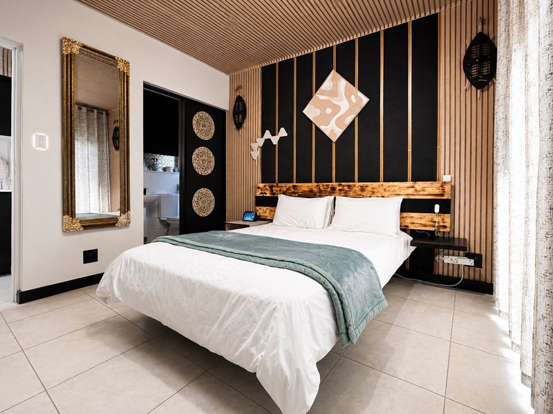 Modern bedroom featuring a unique slatted timber ceiling, decorative timber wall paneling, tiled flooring, and a custom built-in headboard.