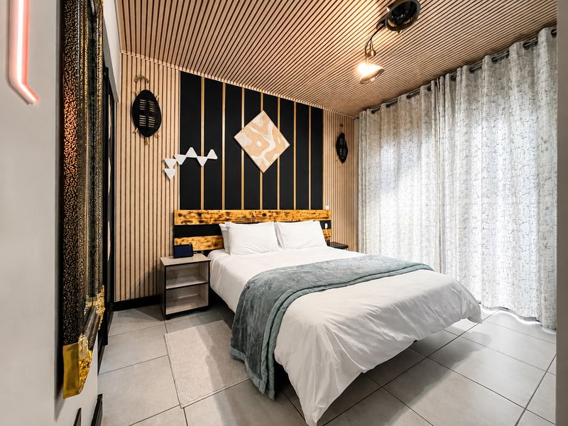 Modern bedroom featuring unique slatted timber ceiling and wall paneling, tiled flooring, and a custom built-in headboard design.