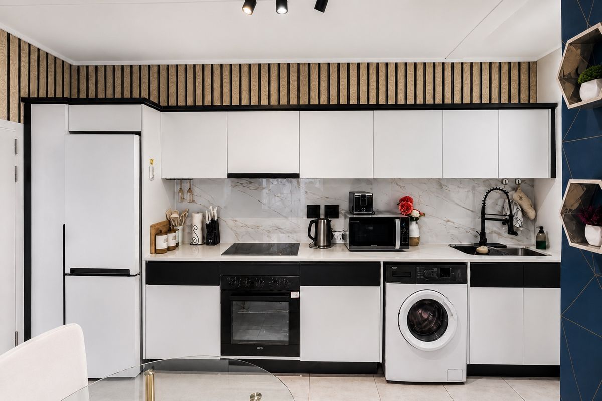 Modern kitchen featuring sleek white and black cabinetry, marble-look splashback, integrated appliances, and contemporary track lighting.