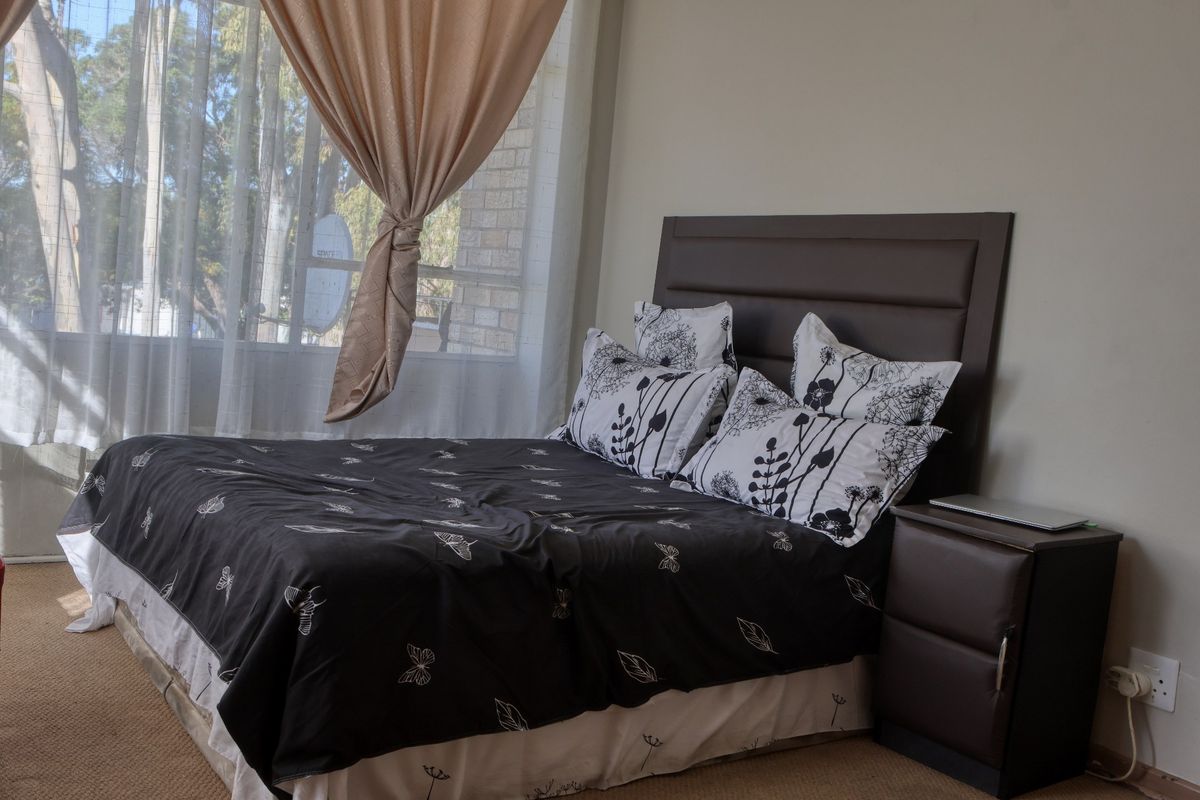 A bedroom featuring carpeted flooring and a large window allowing natural light into the space.