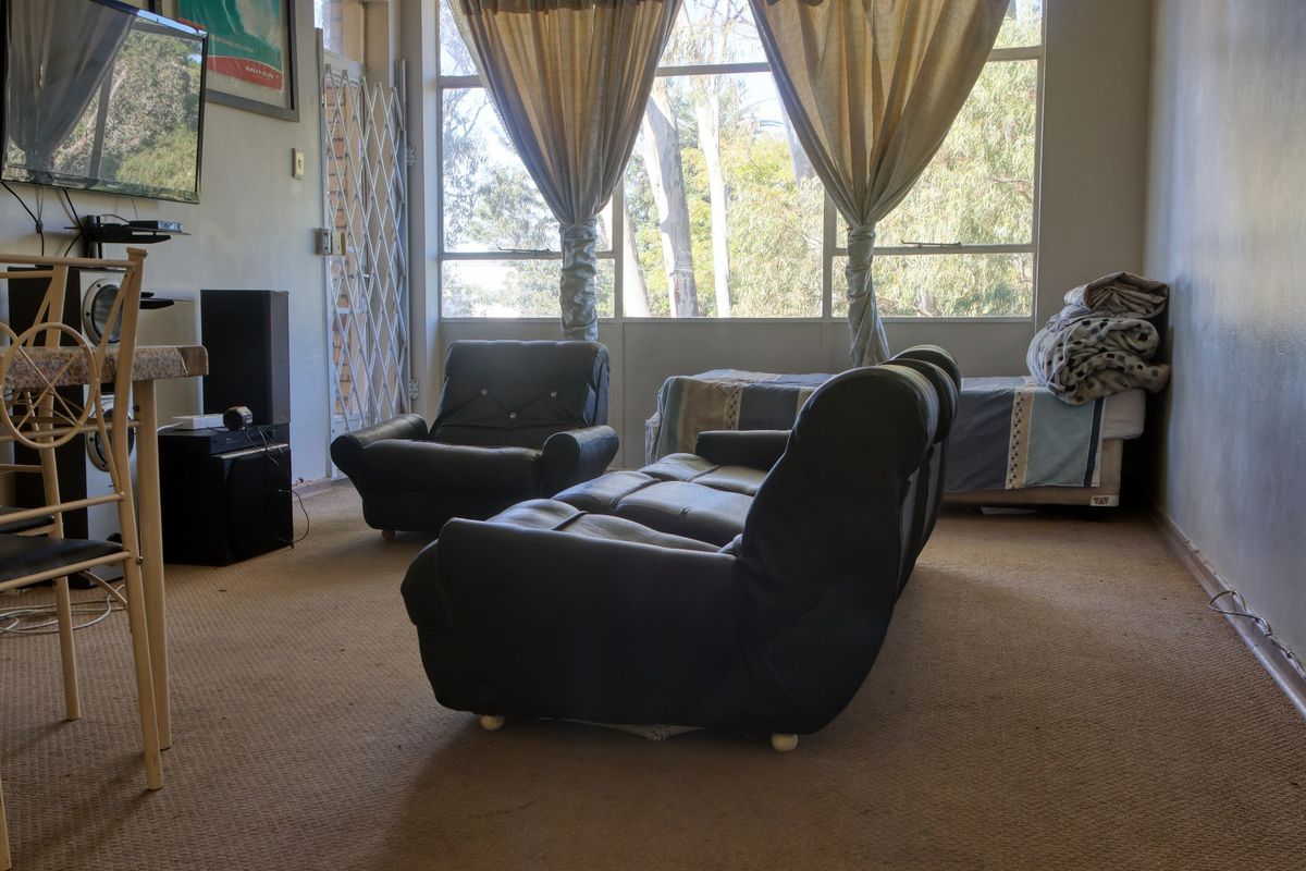A living room area featuring a large window with natural light and a security gate, requiring cosmetic updates to the flooring and finishes.