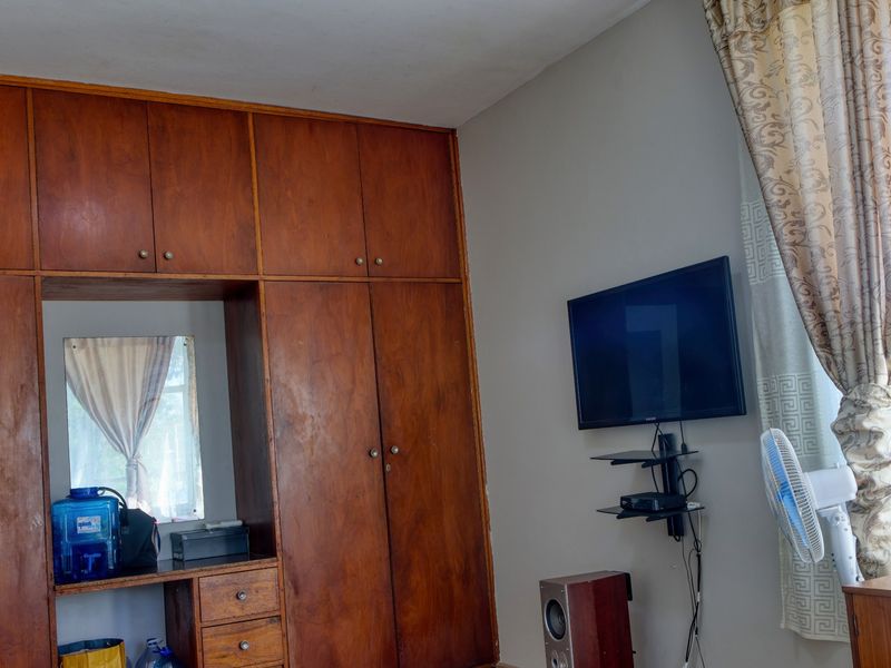 Bedroom featuring floor-to-ceiling built-in wooden wardrobes with integrated vanity mirror and drawer storage.