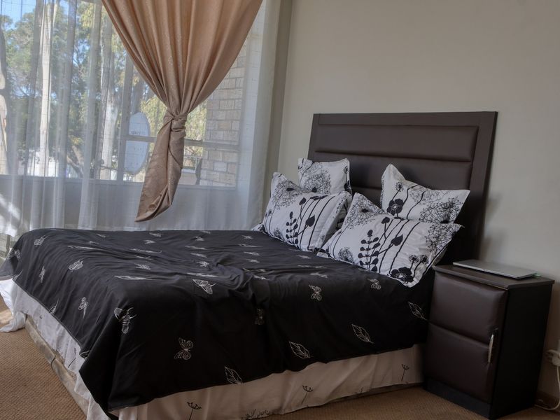A bedroom featuring carpeted flooring and a large window allowing natural light into the space.