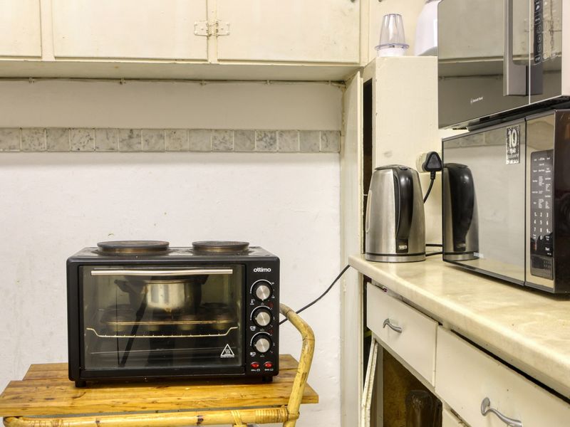 A dated kitchen area featuring original cabinetry, laminate countertops, and a tiled backsplash, currently showing significant signs of wear and tear.