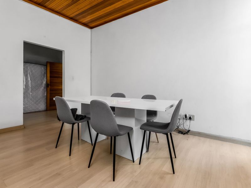 A dining area featuring light-toned laminate flooring and a warm timber-paneled ceiling, providing a neutral foundation for interior design.