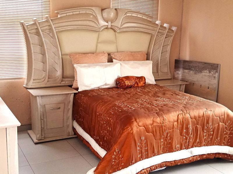 A bedroom featuring tiled flooring and venetian blinds, providing a functional space with neutral wall finishes.