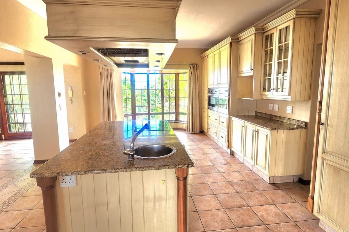 Spacious kitchen featuring a large island with granite countertops, built-in cabinetry, integrated appliances, and a bright bay window area.