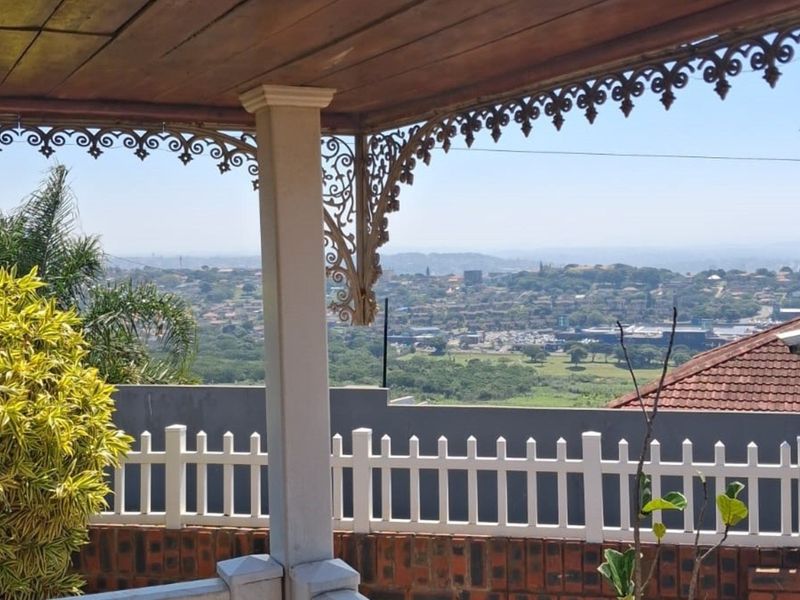 A covered patio featuring decorative ironwork and timber ceiling, offering expansive elevated views over the surrounding neighborhood.