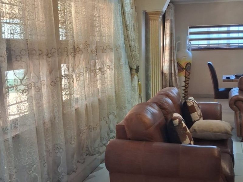A living room area featuring tiled flooring, a decorative column, and window treatments, providing a functional space for relaxation.