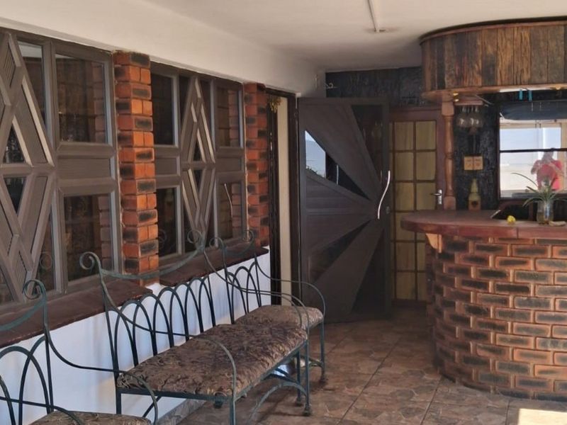 Covered patio area featuring a built-in brick bar, tiled flooring, and decorative timber-framed windows, offering a rustic entertainment space.