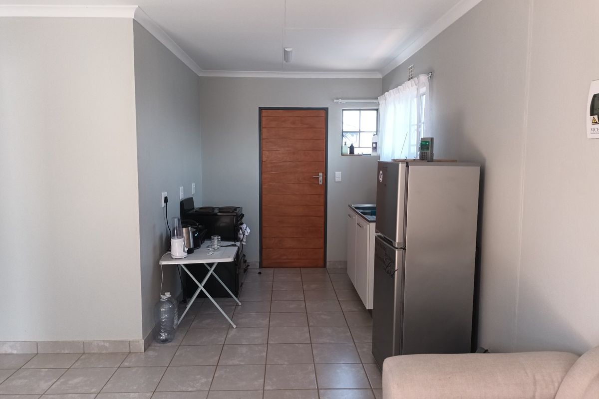 A functional kitchen area featuring tiled flooring, built-in cabinetry, a sink, and a wooden door, providing a clean and practical space.