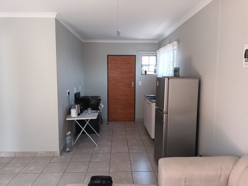 A functional kitchen area featuring tiled flooring, built-in cabinetry, a sink, and a wooden door, providing a clean and practical space.