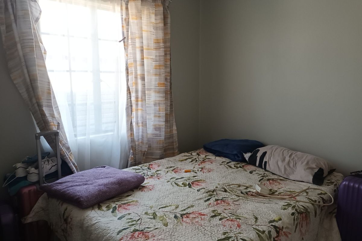 A standard bedroom featuring a window with installed curtain rails, providing natural light to the space.