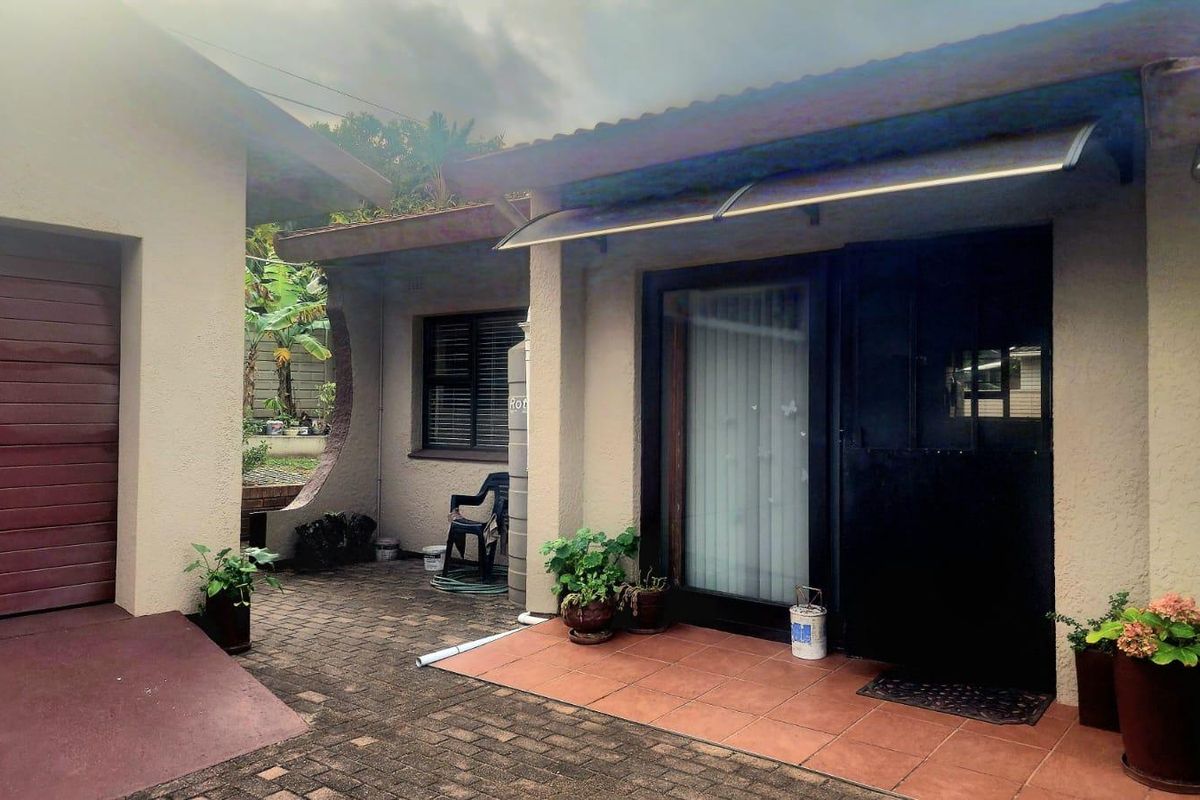 A paved rear courtyard area featuring a tiled patio, garage access, and a water tank, providing a functional outdoor space.