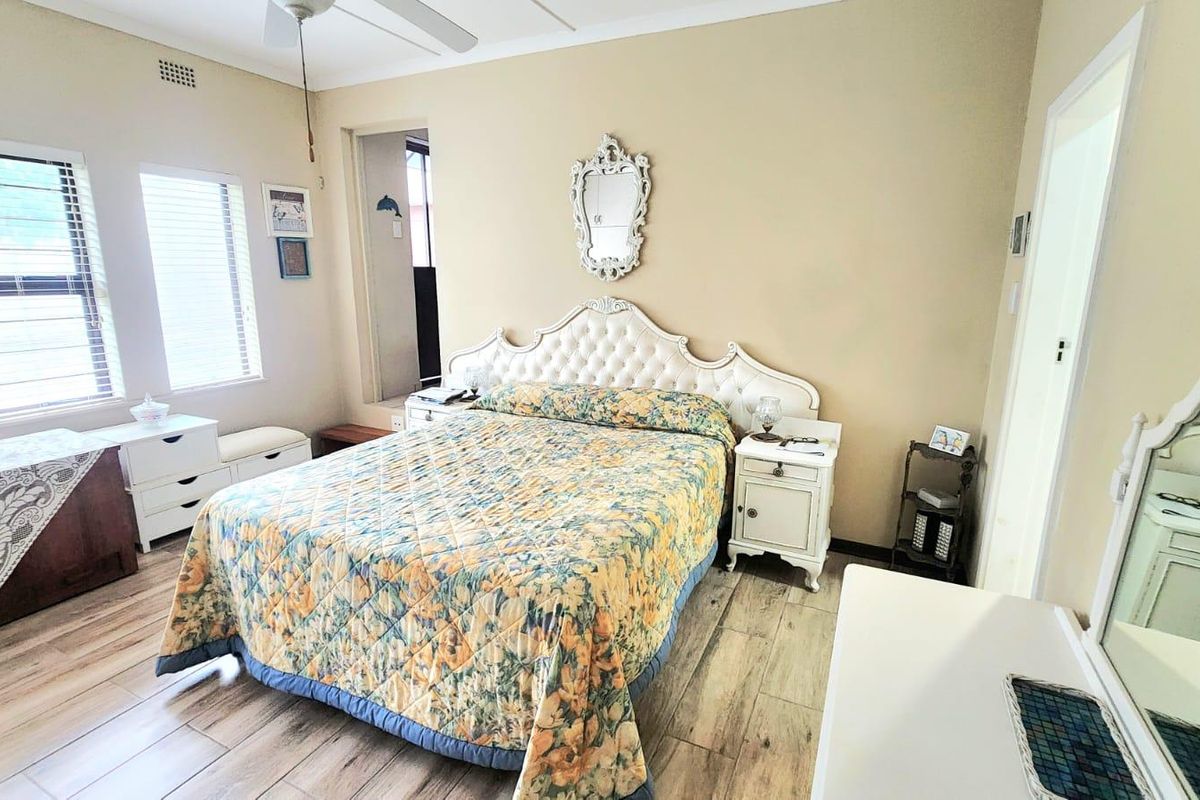A well-lit bedroom featuring wood-look tile flooring, a ceiling fan, and neutral wall tones, offering a comfortable and functional living space.