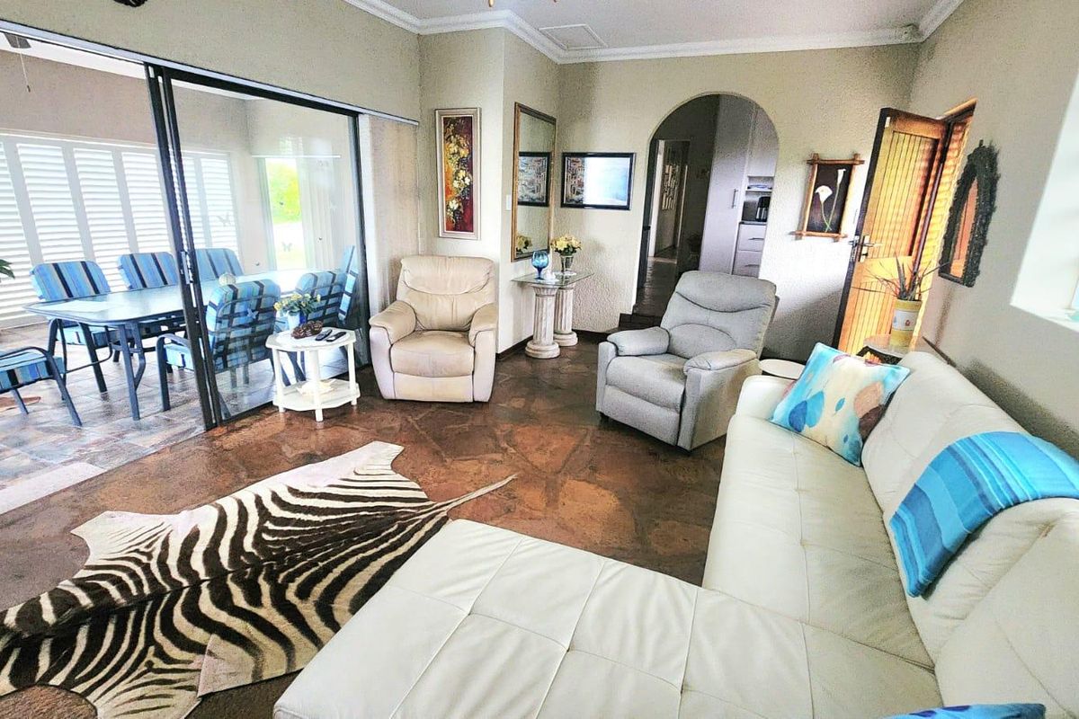 Spacious living room featuring stone flooring, coved ceilings, and large sliding glass doors providing seamless access to the outdoor patio area.
