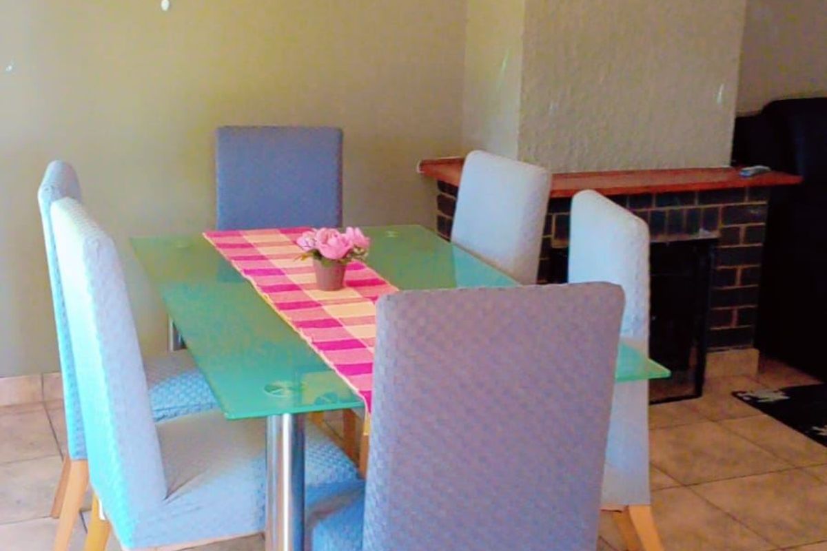 Dining area featuring tiled flooring and a built-in brick fireplace, providing a functional space for meals.