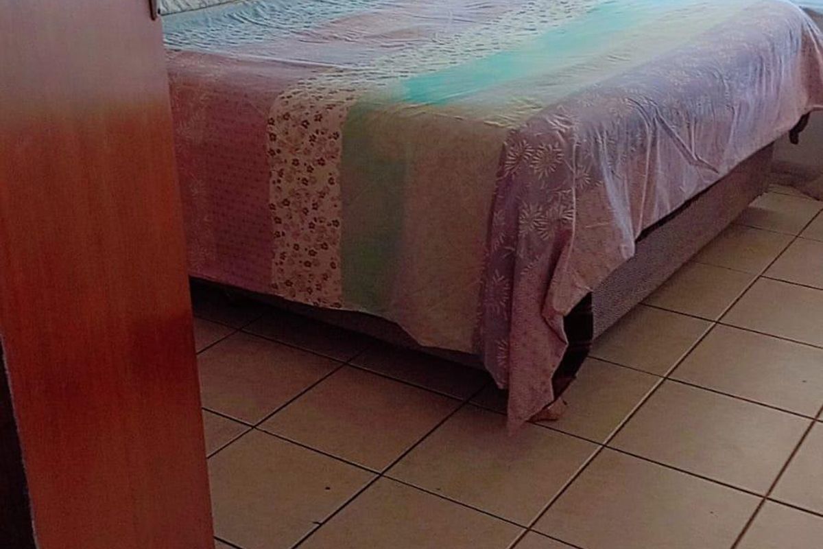 A bedroom featuring tiled flooring and a window fitted with a security gate.