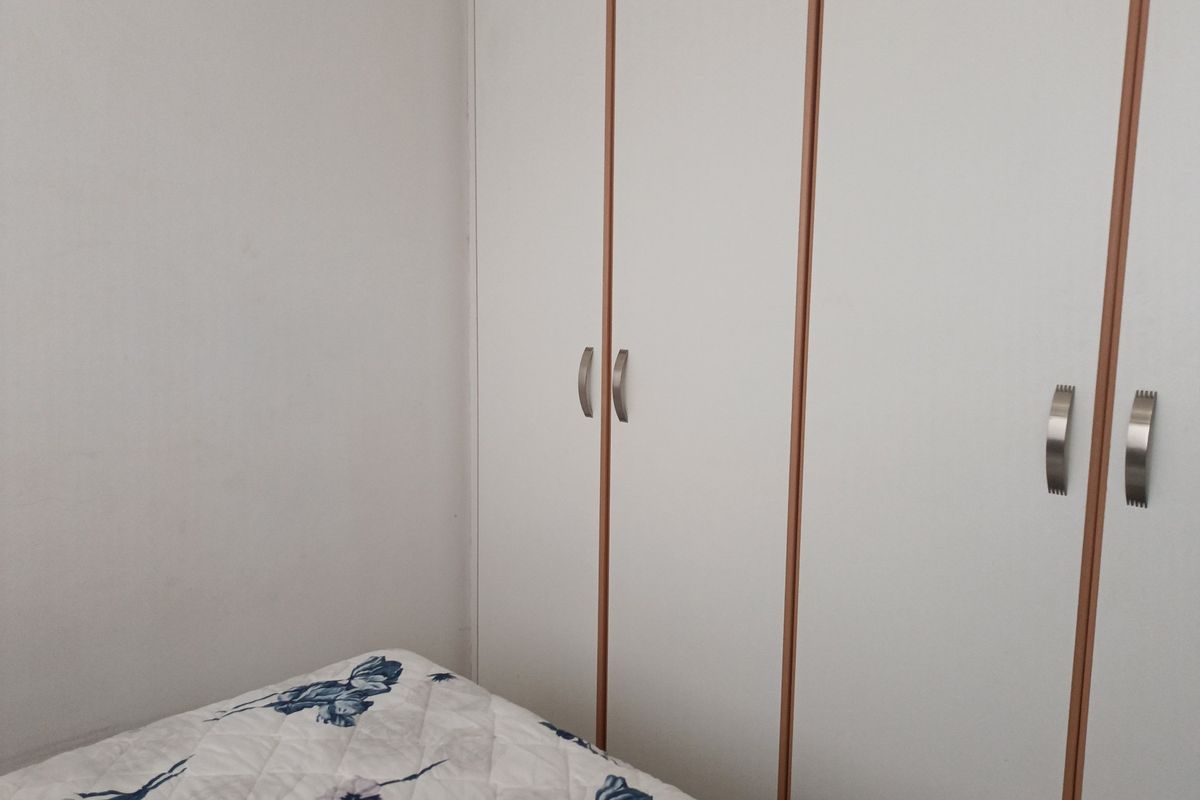 A bedroom featuring white built-in cupboards with metallic handles.