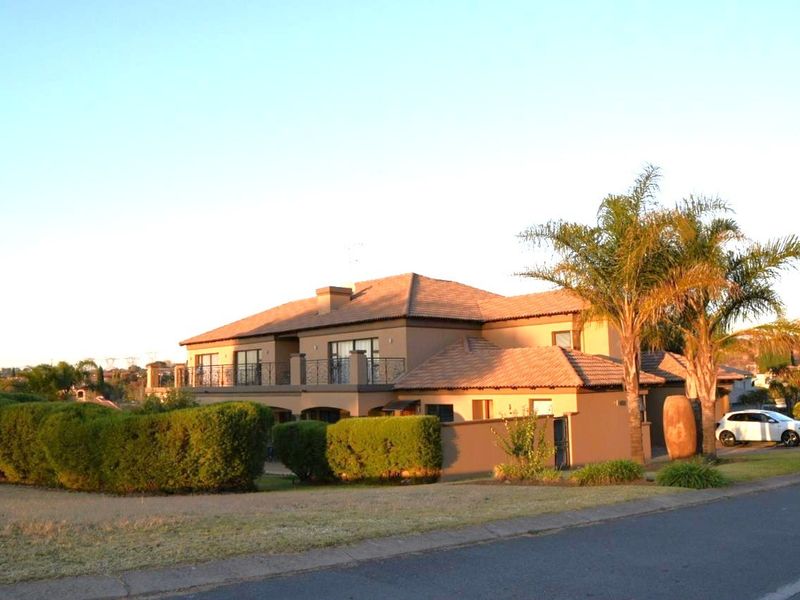 A well-maintained double-story residential property featuring a tiled roof, balcony with wrought iron railings, and a landscaped front garden.
