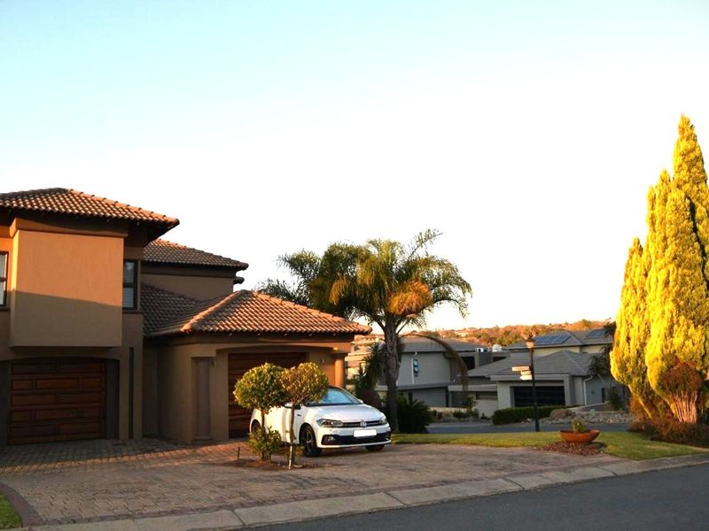 Front elevation of a modern residential house featuring a paved driveway, double garage, and well-maintained exterior finishes in a suburban setting.