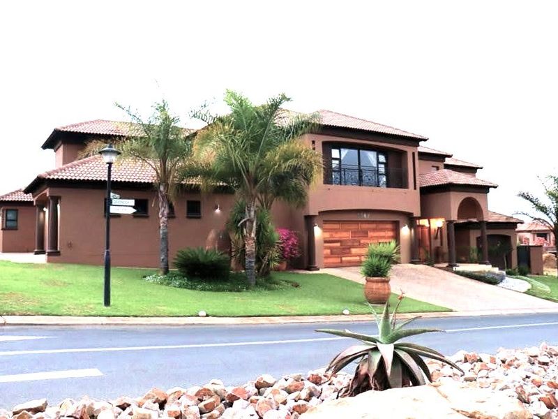 A well-maintained double-story residential home featuring a tiled roof, stucco exterior, and an integrated double garage with a paved driveway.