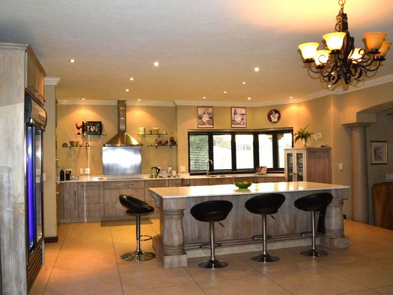 Spacious kitchen featuring a large central island with stone countertops, stainless steel extractor fan, ample cabinetry, and recessed lighting throughout.