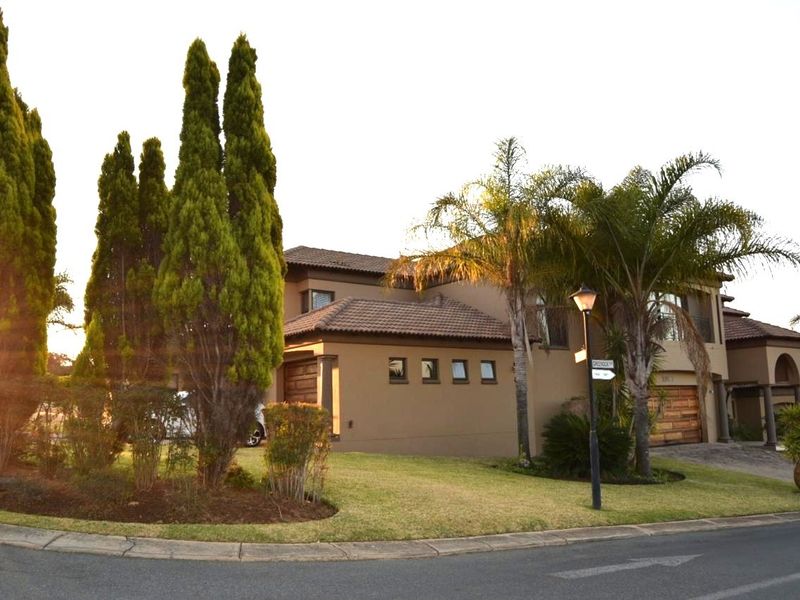 A well-maintained double-story residential property featuring a tiled roof, double garage, and established garden, situated on a corner lot.
