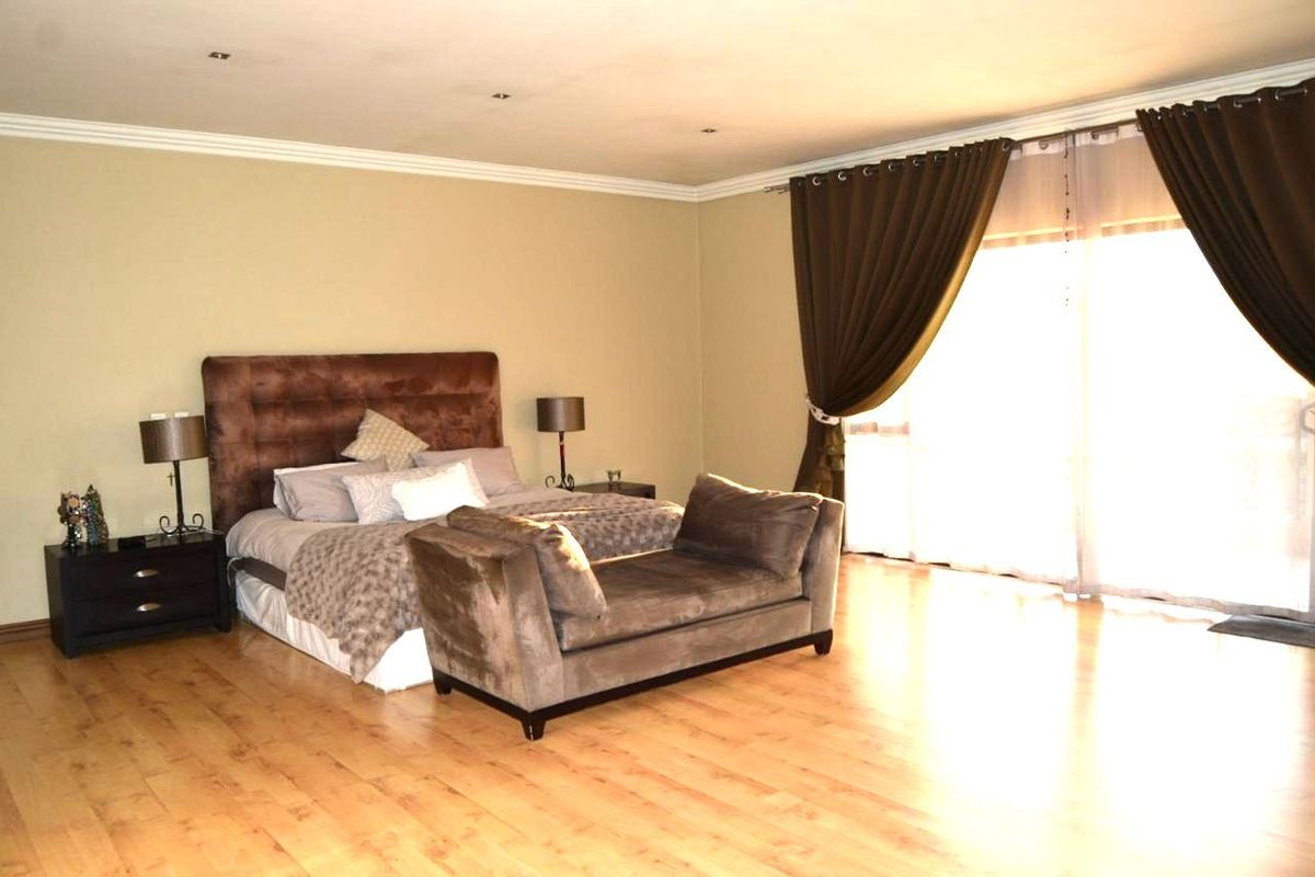Spacious bedroom featuring warm laminate flooring, recessed downlighting, crown molding, and large sliding glass doors providing ample natural light.