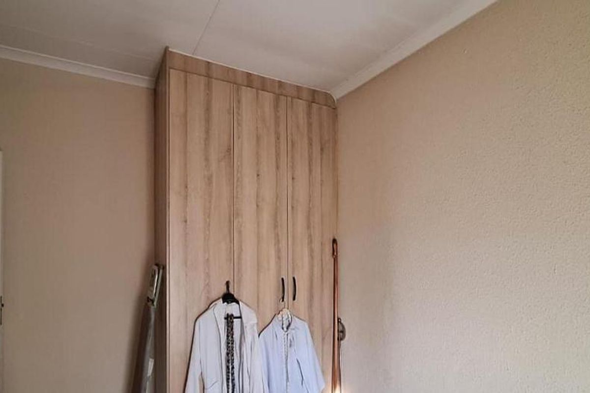 A bedroom featuring a light wood-finish built-in wardrobe and simple cove cornicing.