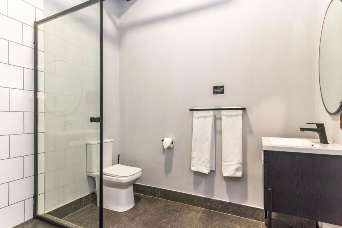 Modern bathroom featuring a walk-in shower with black-framed glass screen, white subway tiling, vanity cabinet with basin, and contemporary black fixtures.