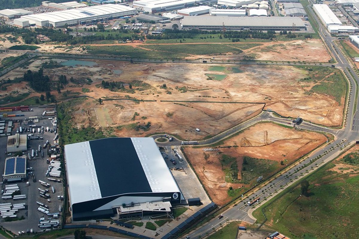 Aerial view of a large commercial warehouse facility with extensive surrounding undeveloped land and direct road access.