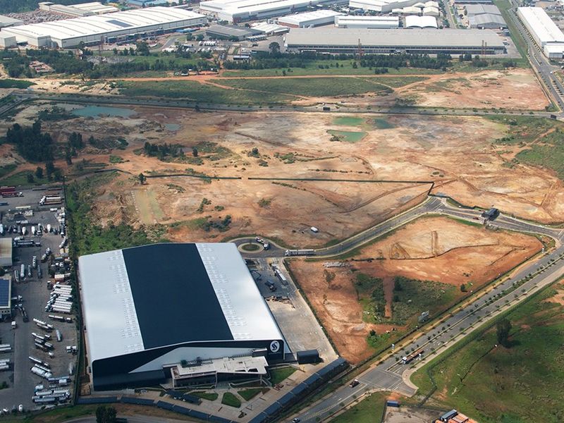 Aerial view of a large commercial warehouse facility with extensive surrounding undeveloped land and direct road access.