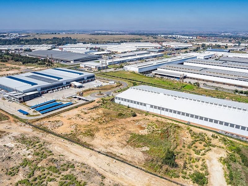 Aerial view of a large-scale commercial industrial park featuring multiple warehouse facilities, paved access roads, and surrounding undeveloped land.