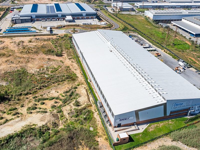 Aerial view of a large industrial warehouse facility featuring a metal roof, loading bays, and paved access roads within a commercial estate.
